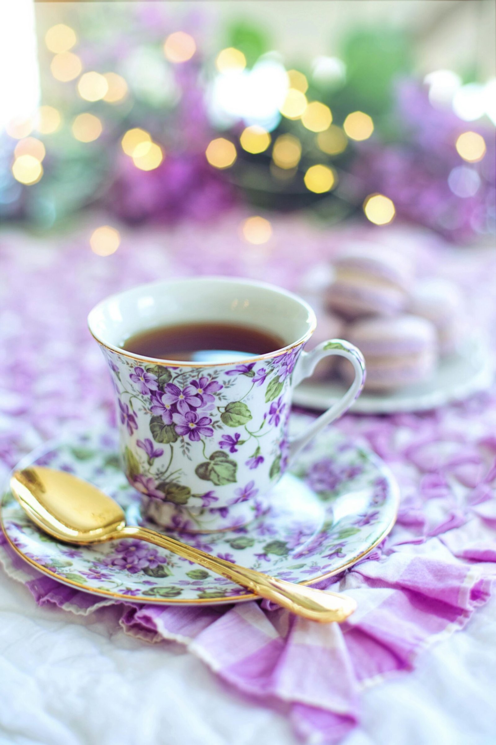 Charming floral teacup with a golden spoon, perfect for a serene teatime with macarons.
